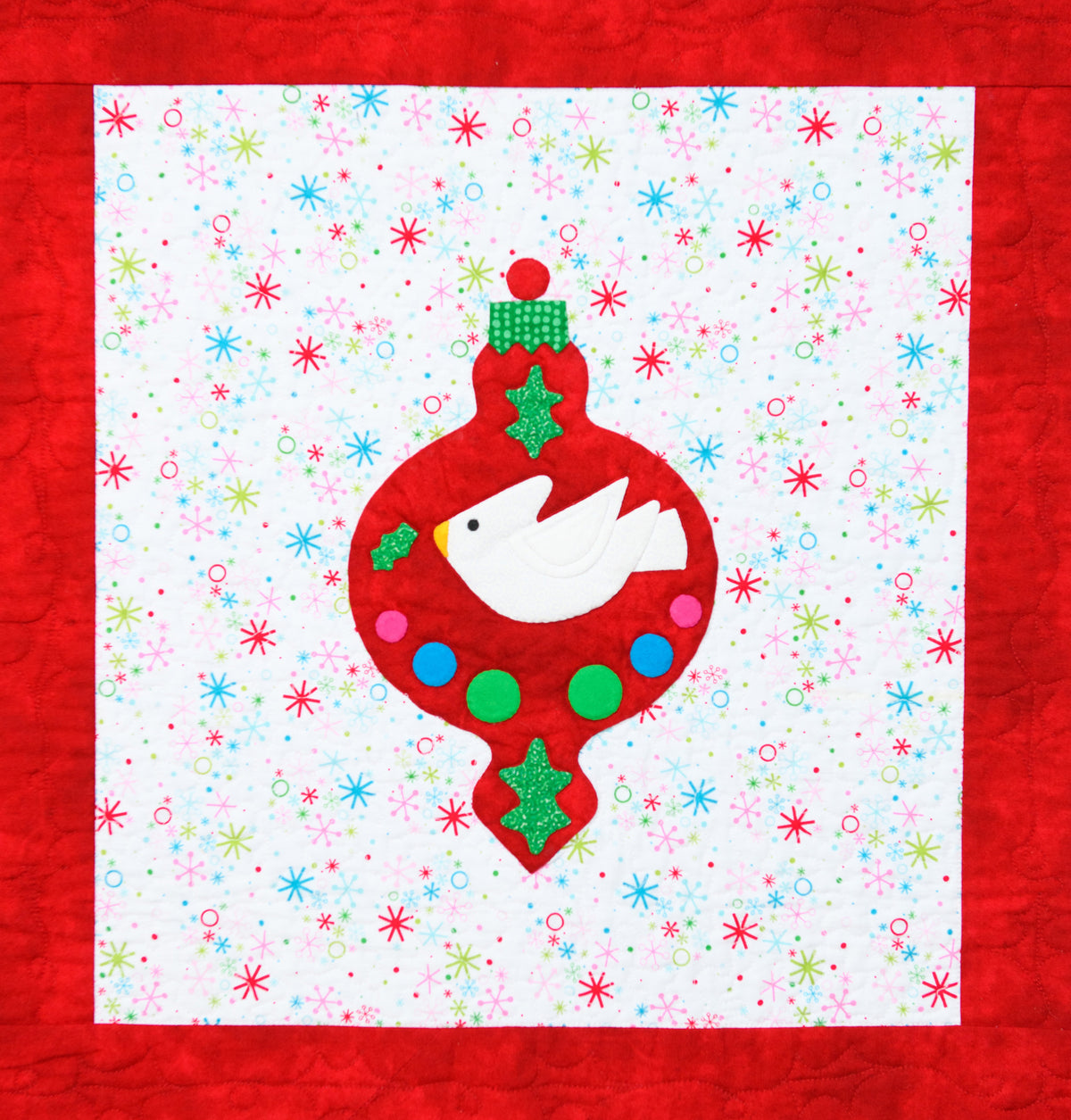 Dove Ornament appliqué quilt pattern on a red ornament and Christmas background fabric