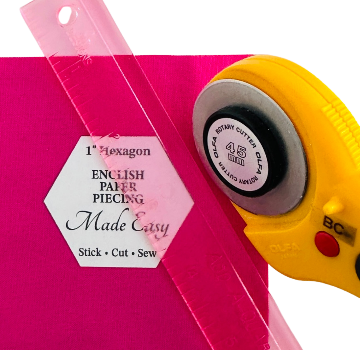 Rotary cutter and ruler on a pink background with text