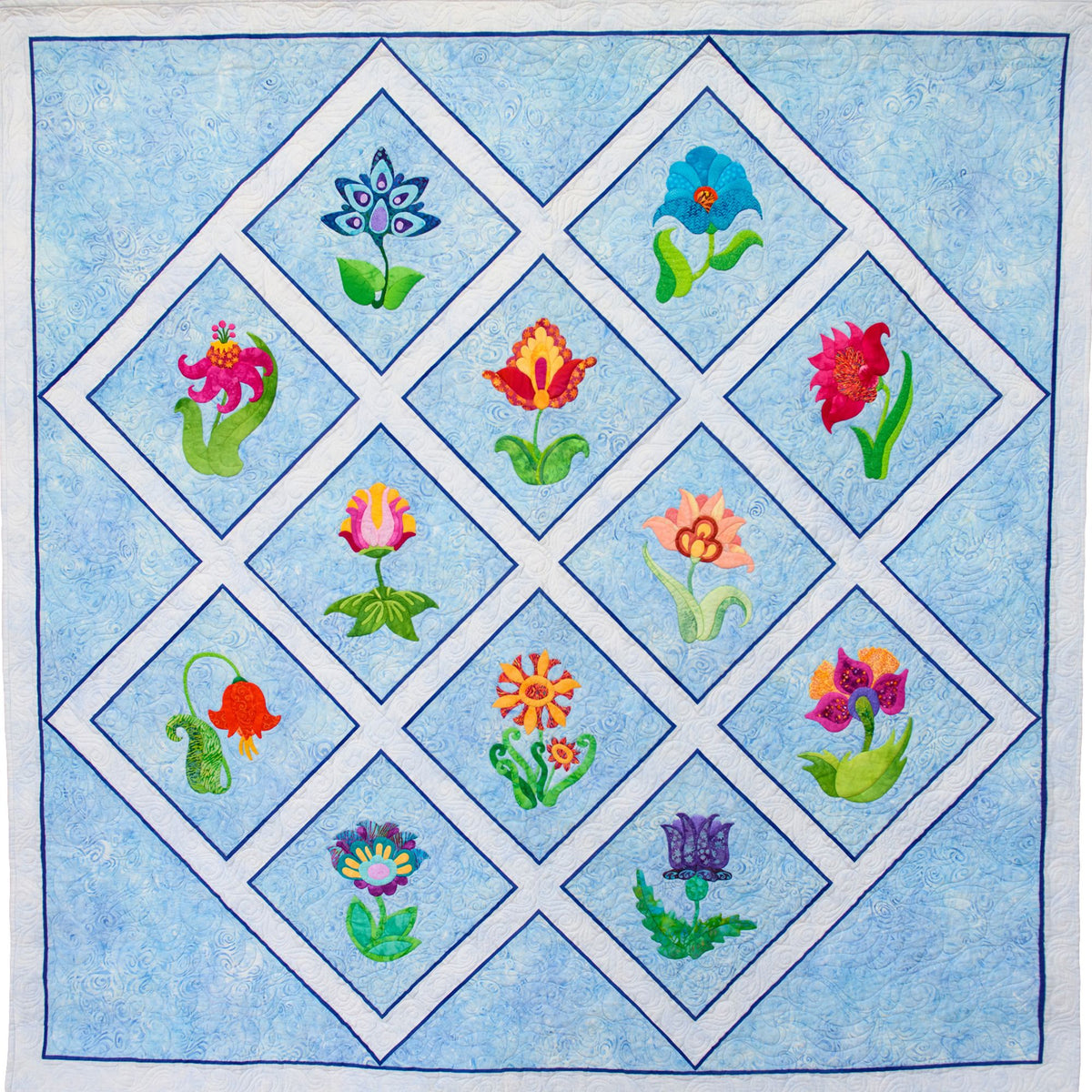 A square quilt or textile panel with a light blue background and a large diamond-shaped grid made of white borders. Inside the diamonds are colorful appliqué flowers in pink, blue, orange, purple, yellow, and red, each with green stems and leaves.