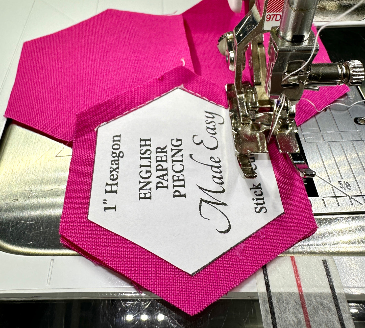 Hexagon English Paper Piecing (EPP) with pink fabric and white paper label on a sewing machine. Straight stitching by machine.