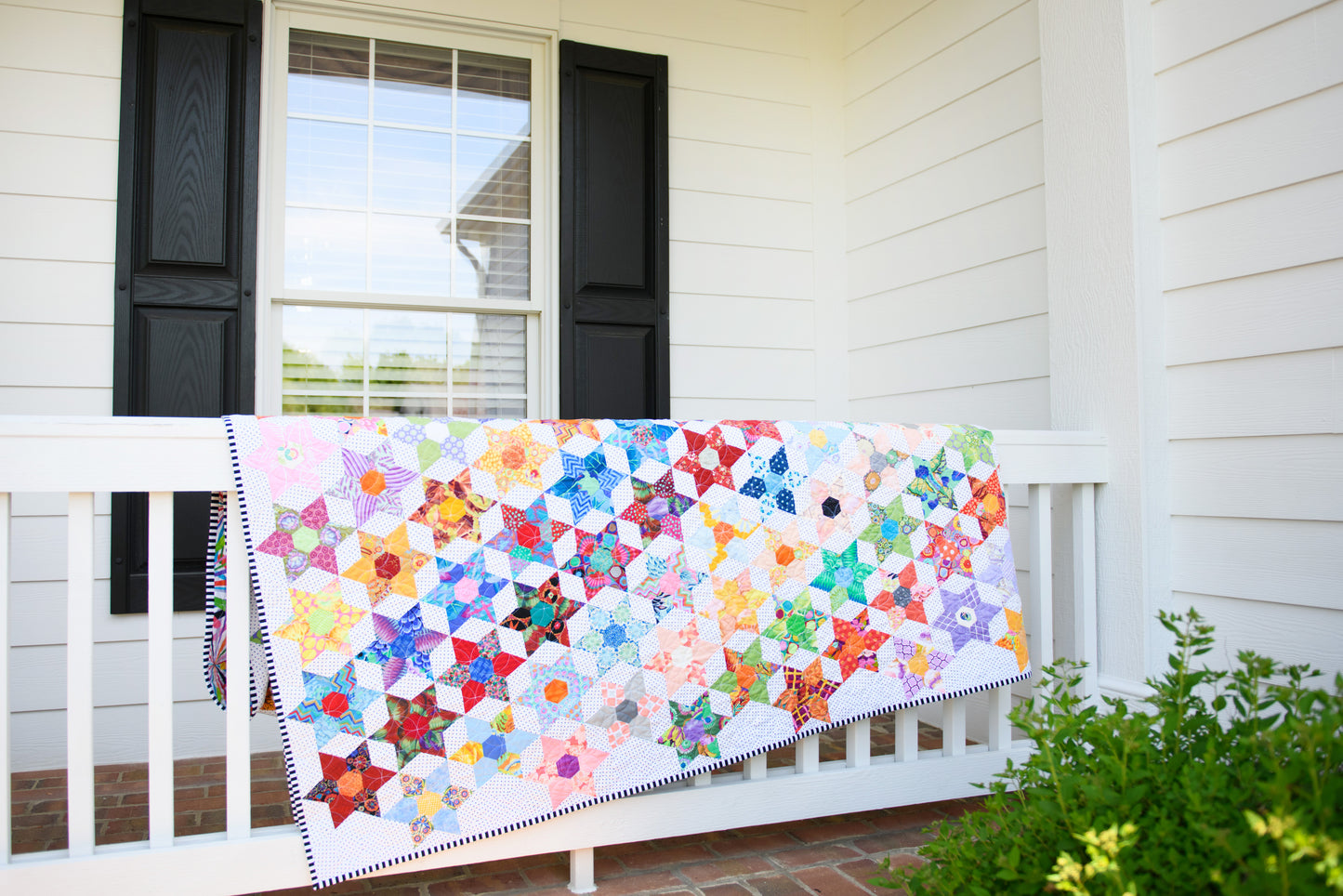 Daisy Chain quilt made with English Paper Piecing Made Easy templates over porch rail